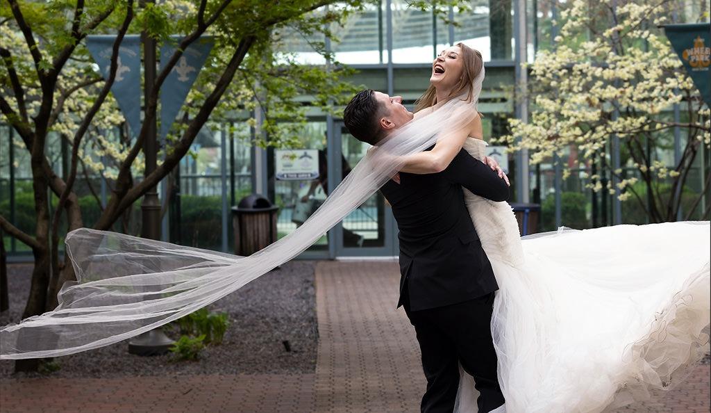 Wedding day portrait of Audrey and Scott by M Carter Photography, with Scott twirling Audrey in the hotel courtyard, shot on location with natural lighting.